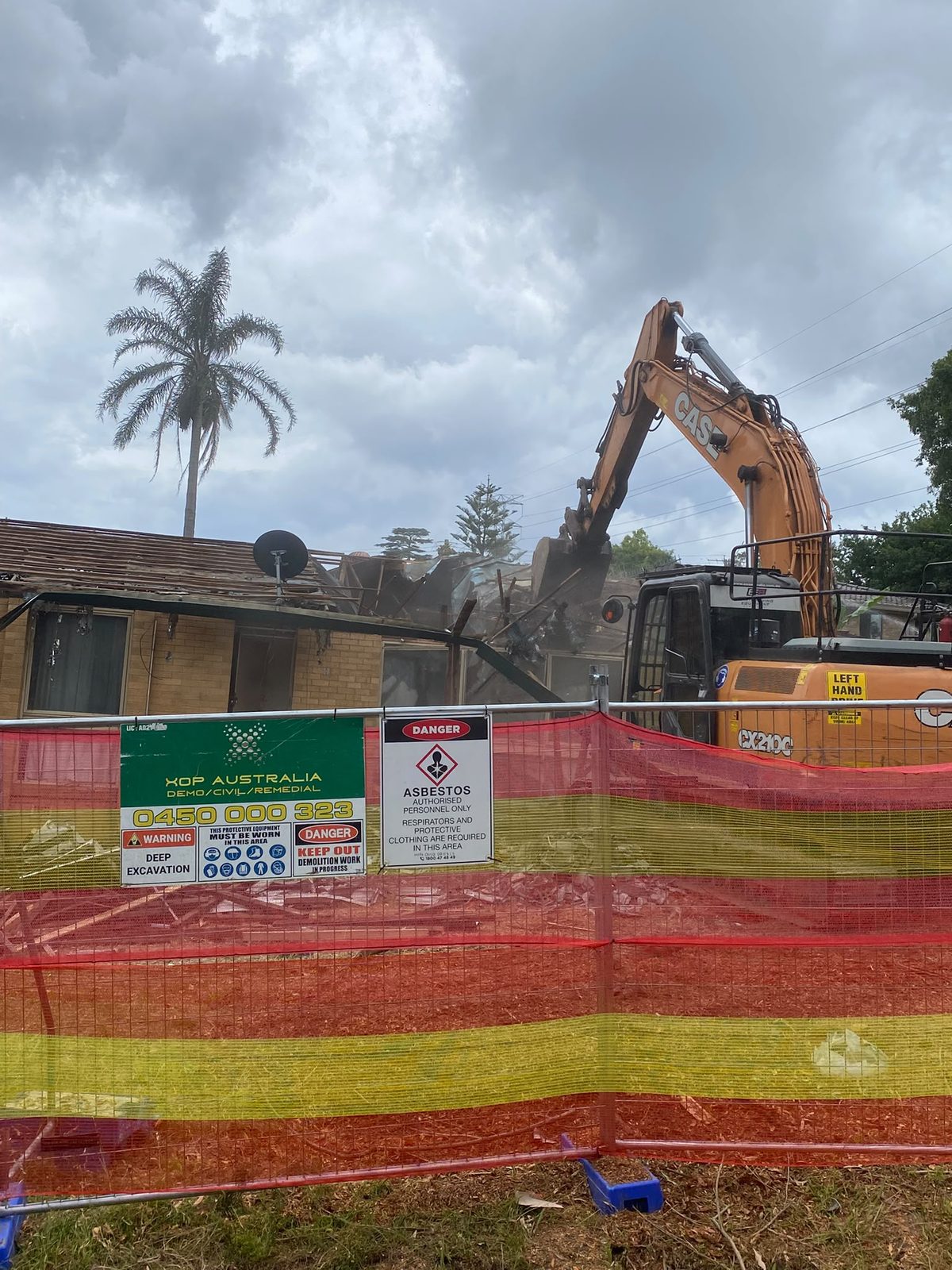 XOP site sign and asbestos danger sign on the fence of a house demolition