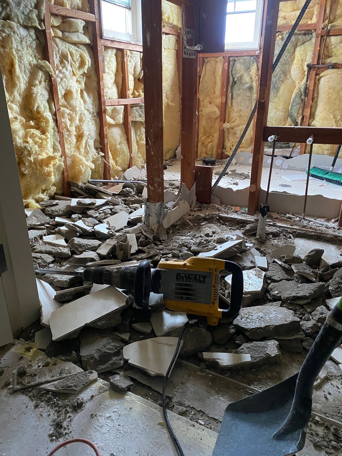 Bathroom stripped back with tiles broken out and insulation exposed